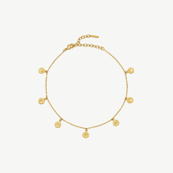 A thin gold anklet with 7 small circular charms spread out evenly across the chain.