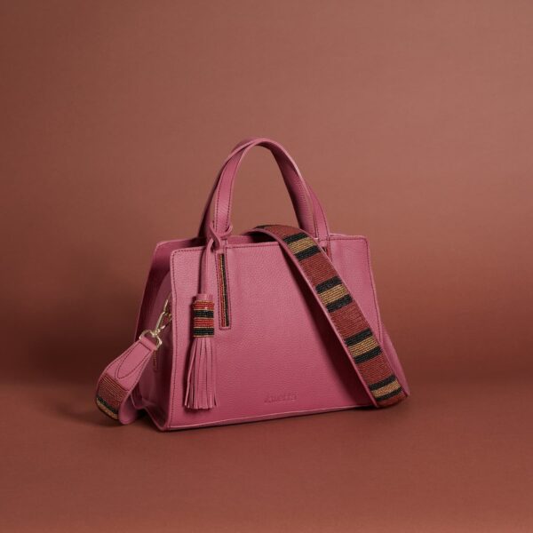 A pink leather handback with a red, gold, and black beaded strap and tassel.