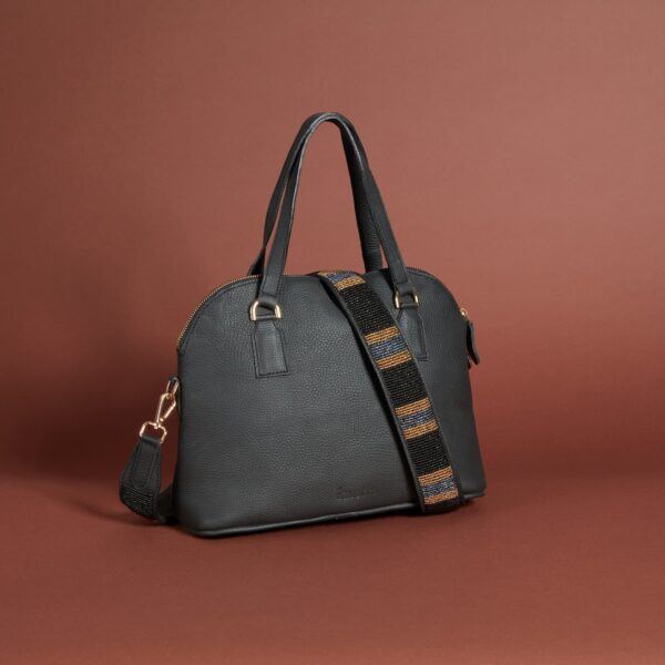 A black leather handbag with a zippered top, handles and a beaded brown and black shoulder strap.