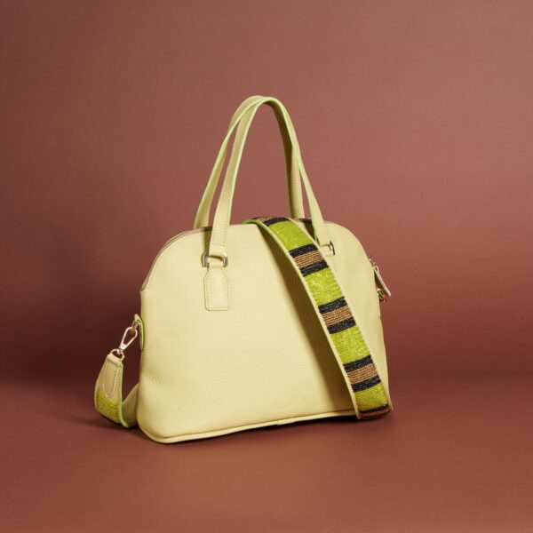 A very pale green handbag with a zippered top, handles and a beaded brown, black, and chartreuse shoulder strap.