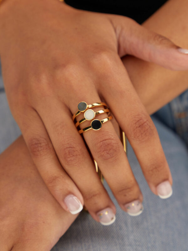 A person wearing a multicolor stacking ring set. A set of three rings. Made of 24K gold-plated recycled brass