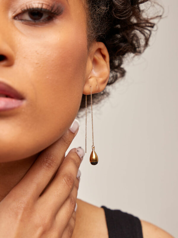 person wearing a 24K gold plated recycled brass chain earrings with recycled horn in black