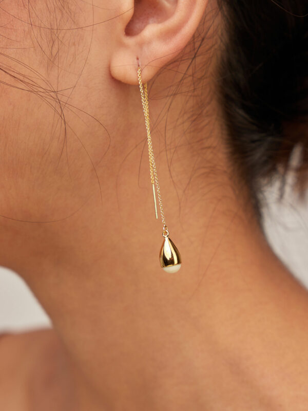 person wearing 24K gold plated recycled brass chain earrings with recycled horn in white
