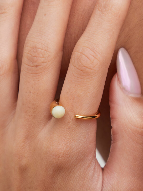 person wearing 24K gold-plated recycled brass ring with recycled horn in white